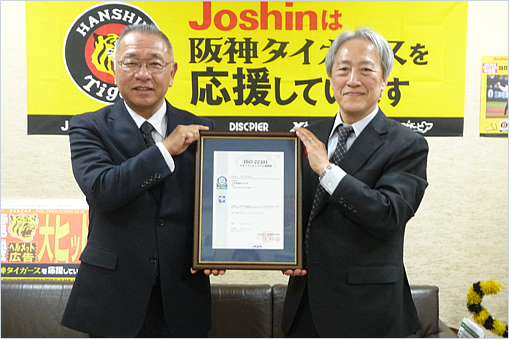 上新電機株式会社　金谷 隆平 副社長（左）と当機構理事 福井 安広
